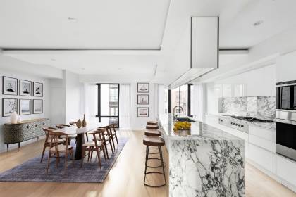 A kitchen with marble counter tops and wooden stools.